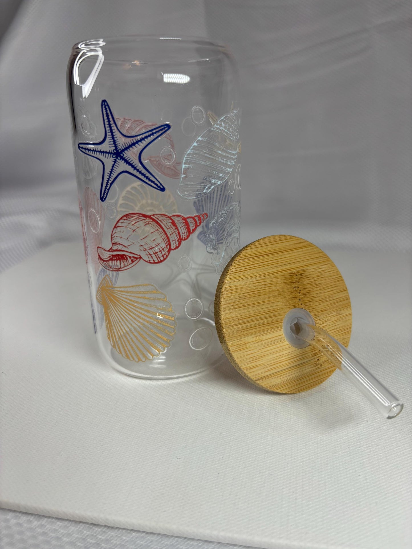 Clear tumbler with starfish and shell designs on a white background