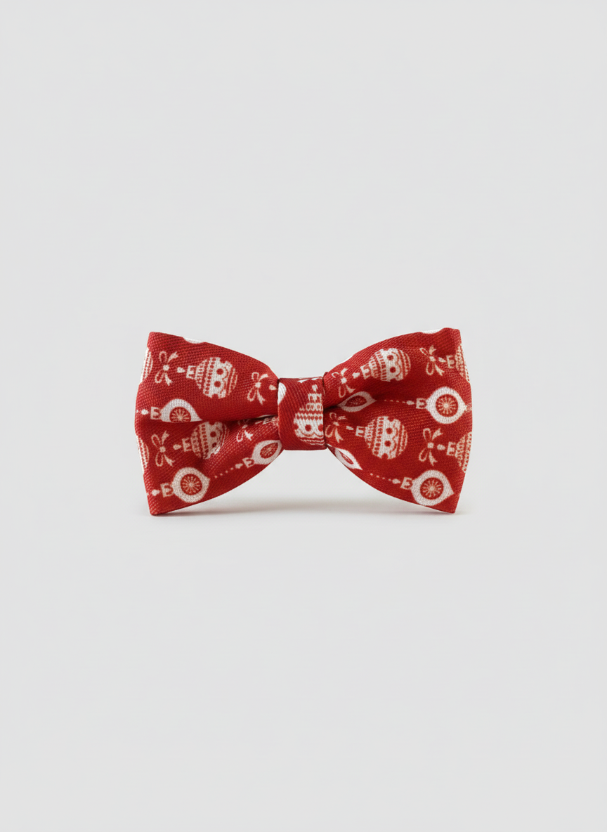 Red bow tie with white patterns on a wooden surface in front of a fireplace.