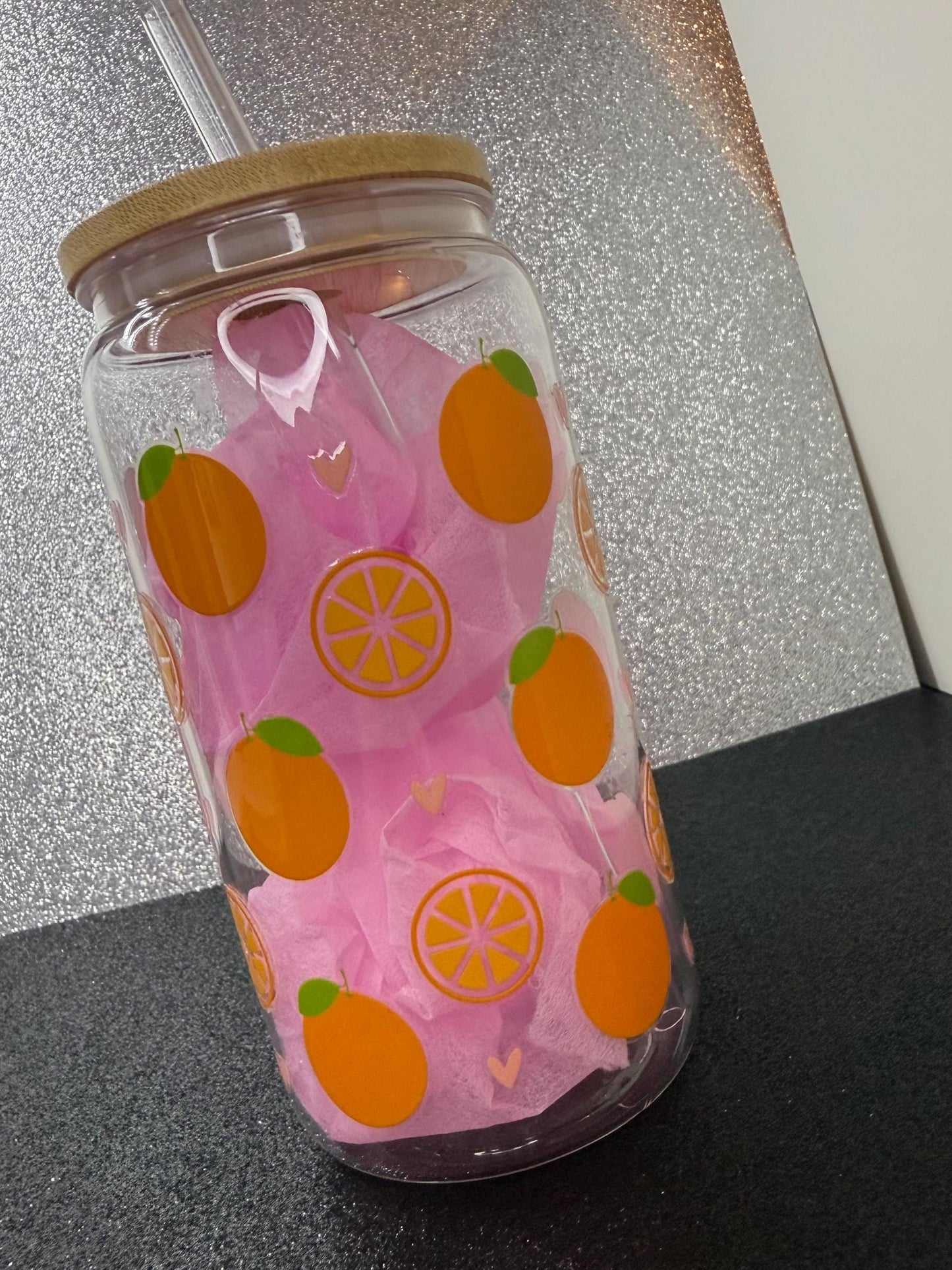 Clear tumbler with orange and green pattern on a reflective surface