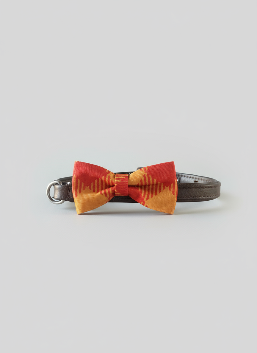 Orange and yellow striped bow tie on a wooden surface with a fireplace in the background