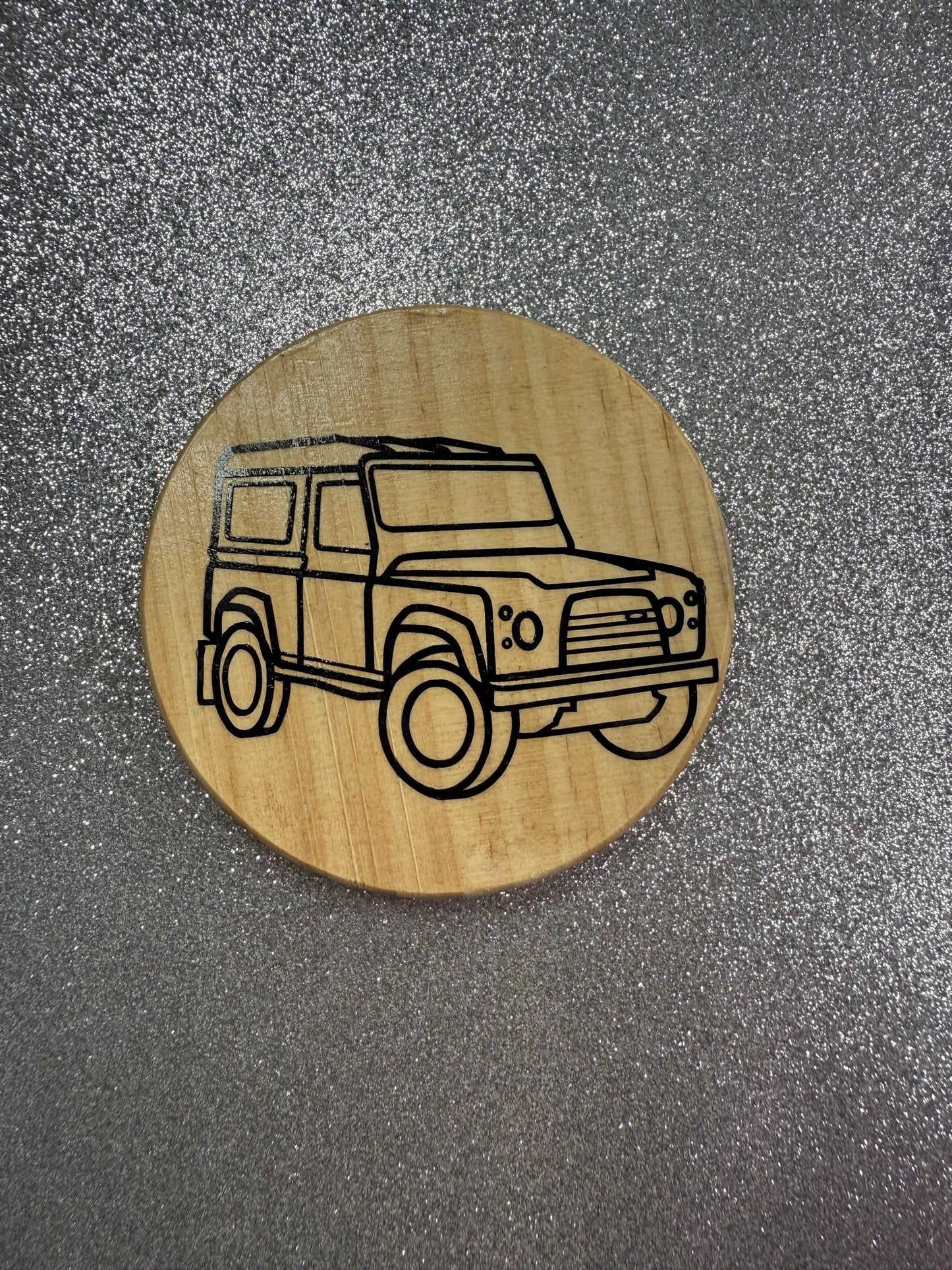 Wooden coaster with a laser-cut vehicle design on a metallic surface