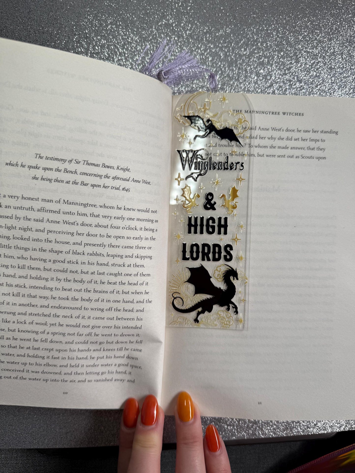 Open book with a bookmark featuring 'Witchfinder's & High Lords' on a metallic surface.