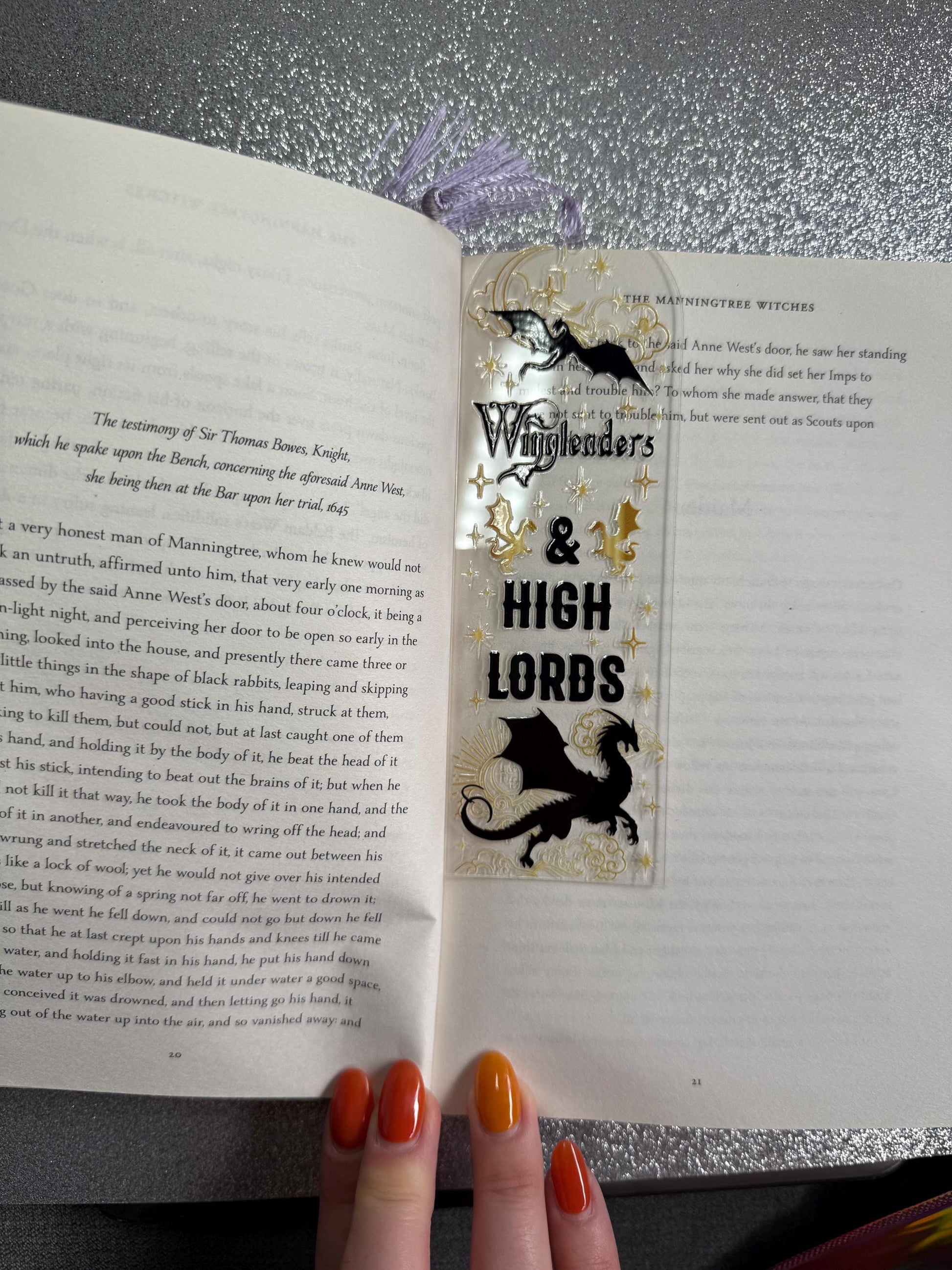 Open book with a bookmark featuring 'Witchfinder's & High Lords' on a metallic surface.