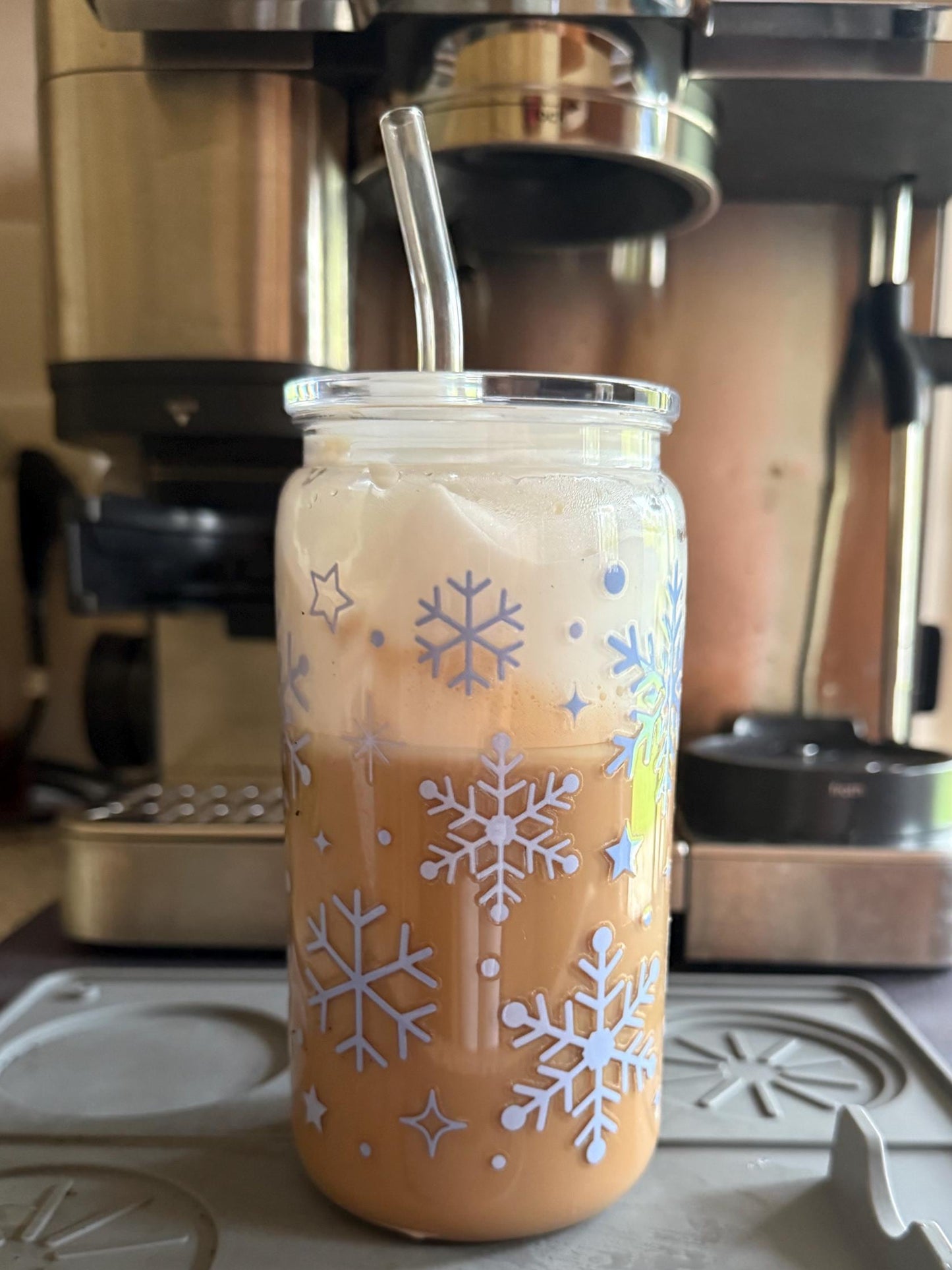 Glass tumbler with snowflake design filled with a beverage on a stovetop.