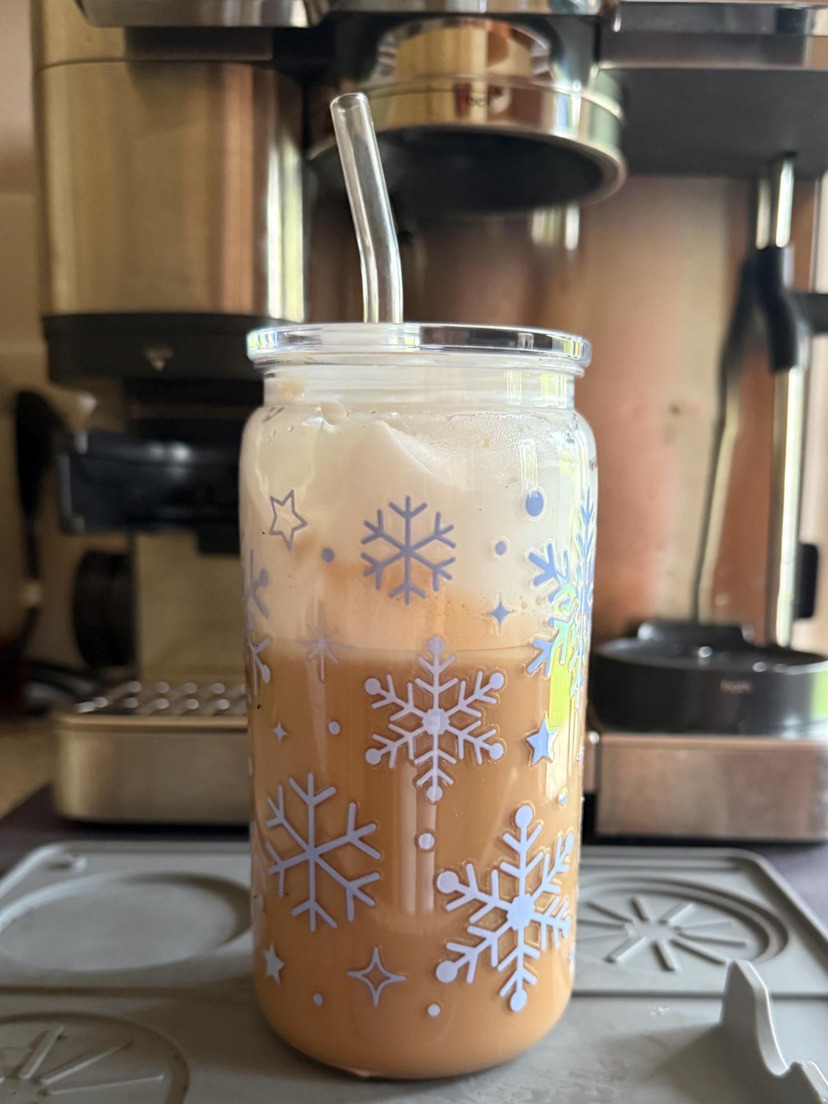 Glass tumbler with snowflake design filled with a beverage on a stovetop.