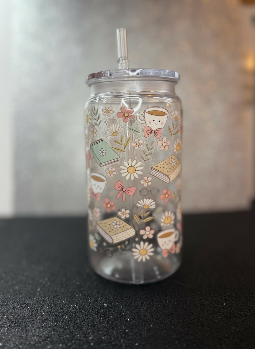 Clear tumbler with floral and coffee cup design on a black surface