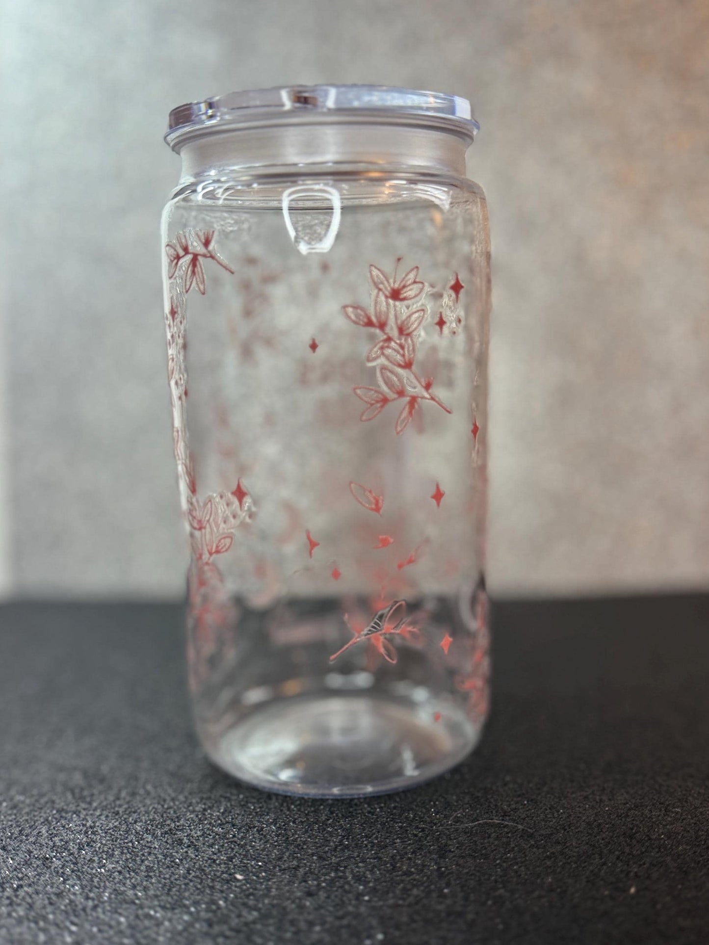 Clear glass jar with floral patterns on a dark surface
