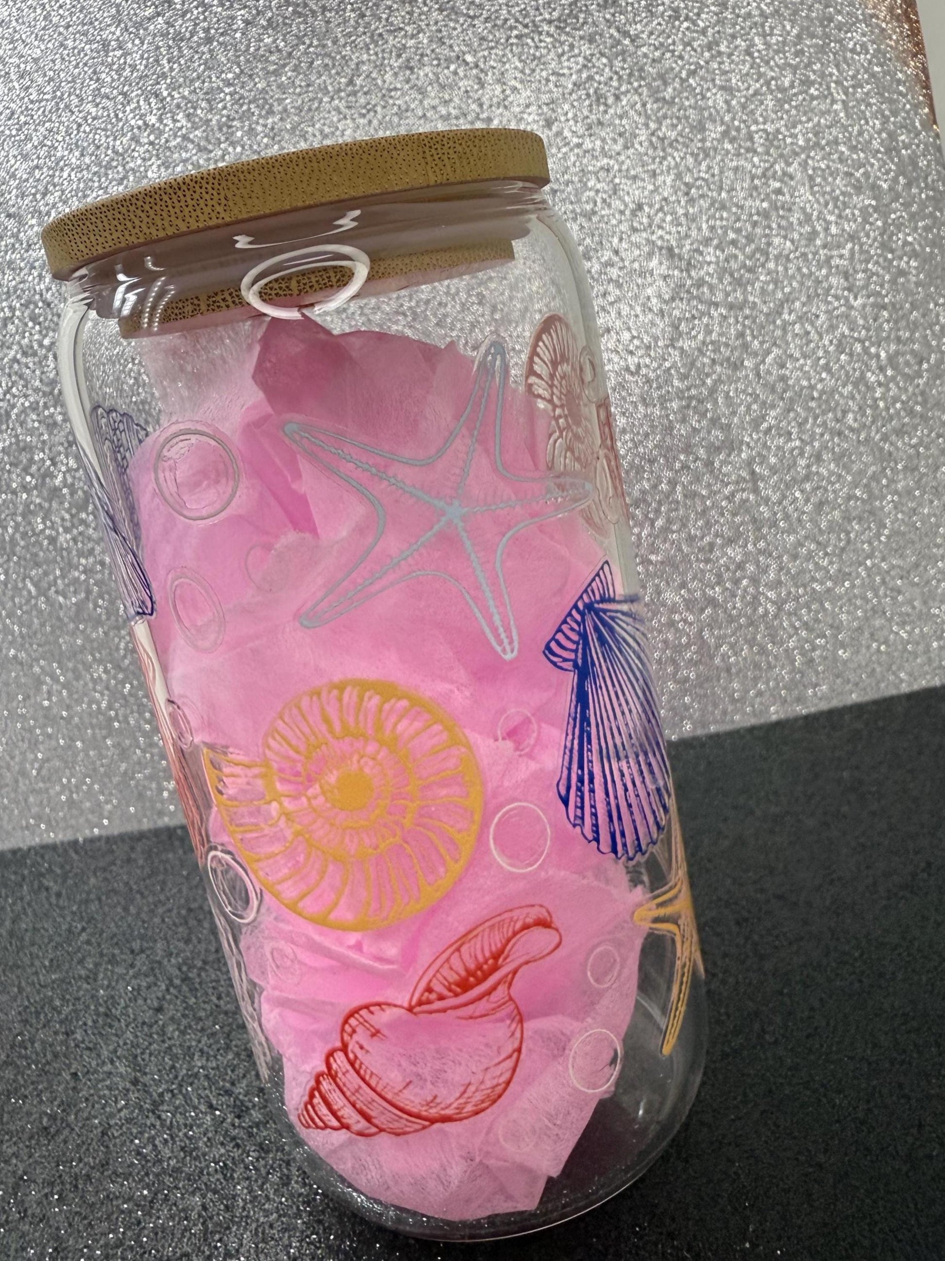 Glass jar with pink sea-themed design on a glittery background