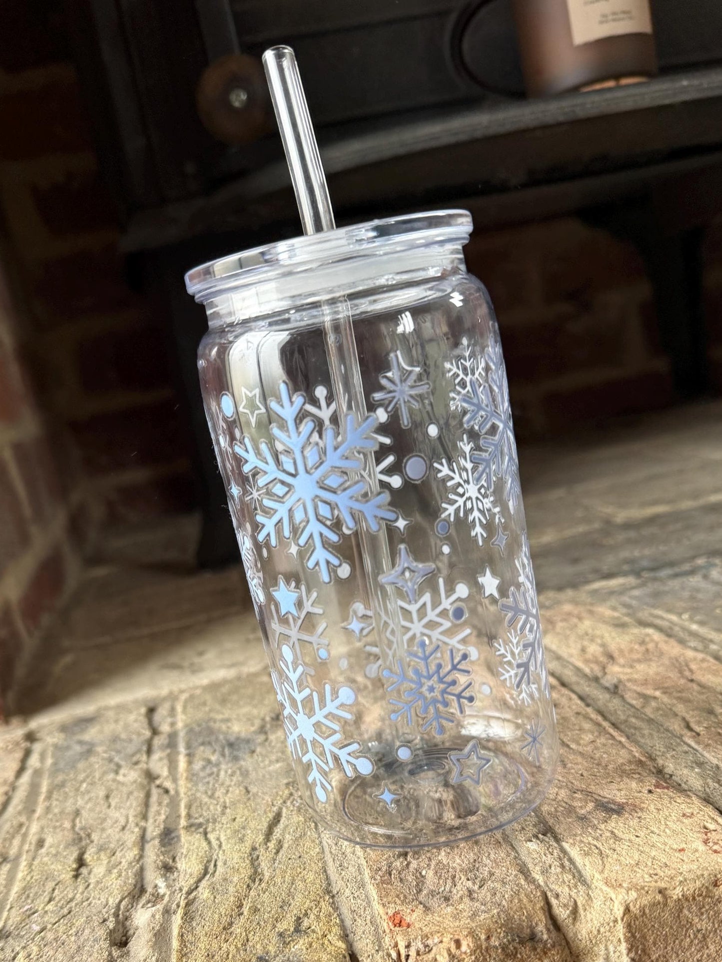 Clear tumbler with snowflake designs on a brick surface