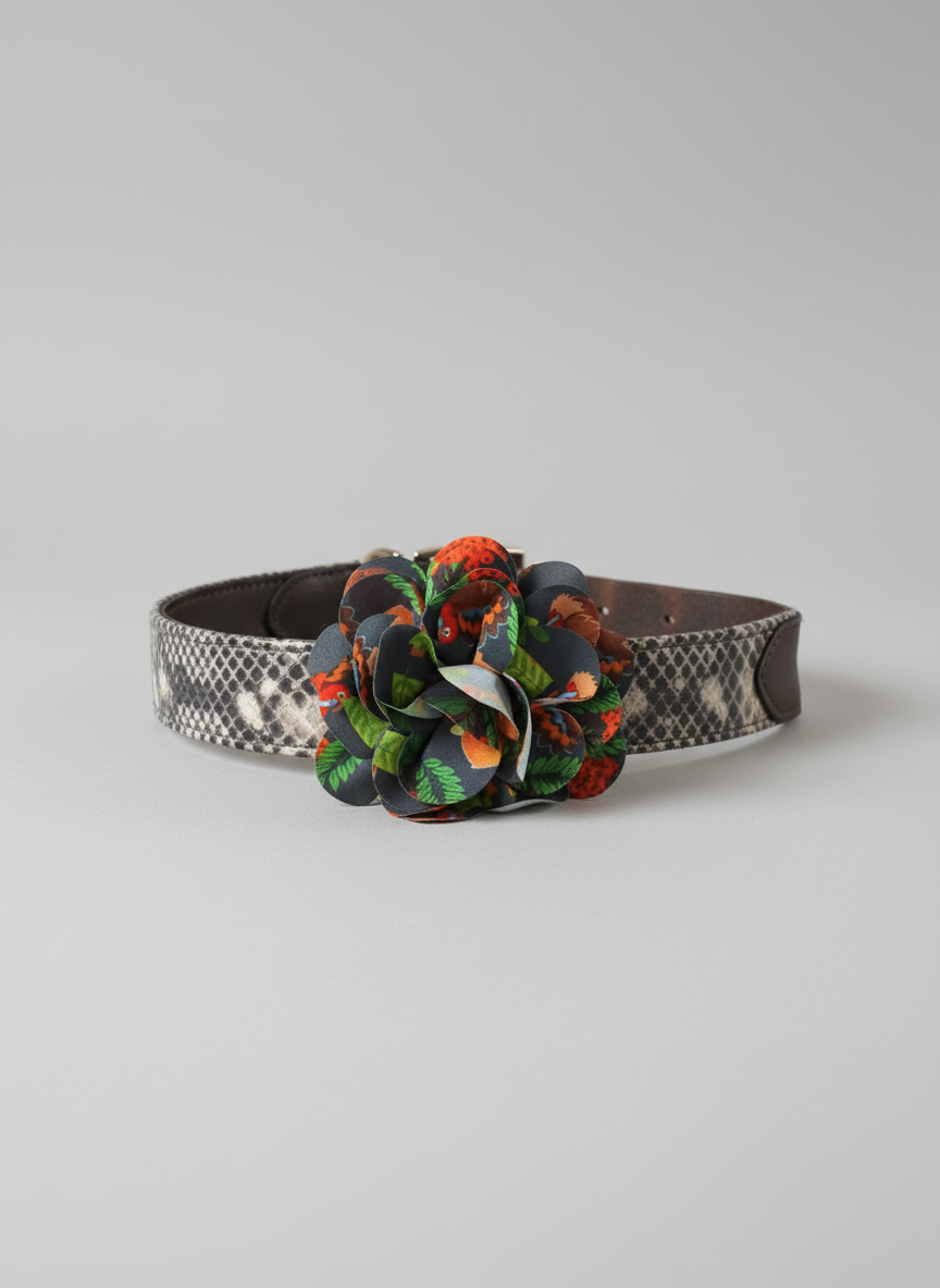 Dog collar with a colorful flower decoration on a wooden surface in front of a fireplace.